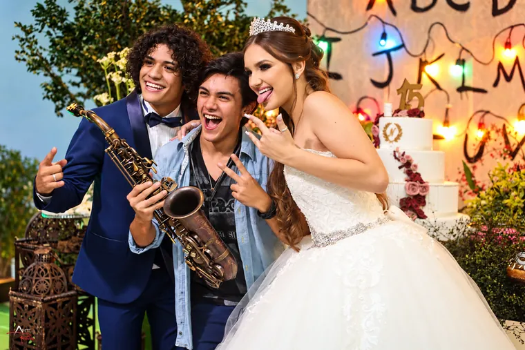 Victor Aguiar com o saxofone a celebrar com os noivos junto ao bolo de casamento, num cenário iluminado com luzes de festa