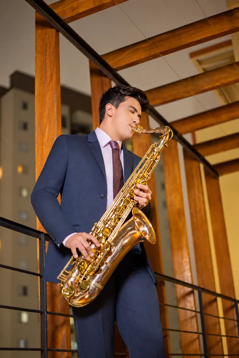 Victor Aguiar a tocar saxofone a solo, de noite, num terraço iluminado